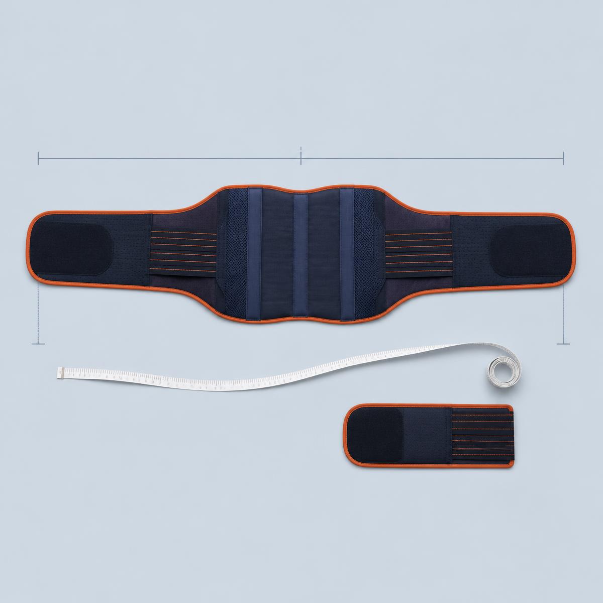 The Emfizo belt laid flat and fully extended beside a tape measure and a separate extension strap, illustrating adjustable fit